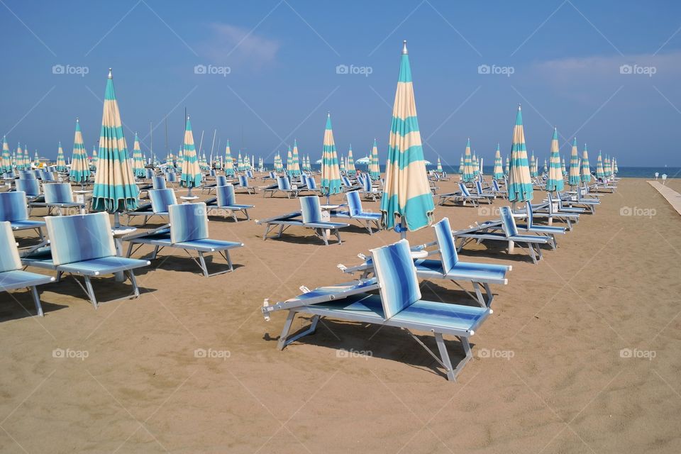 Empty beach with sunlounger and closed parasols 
