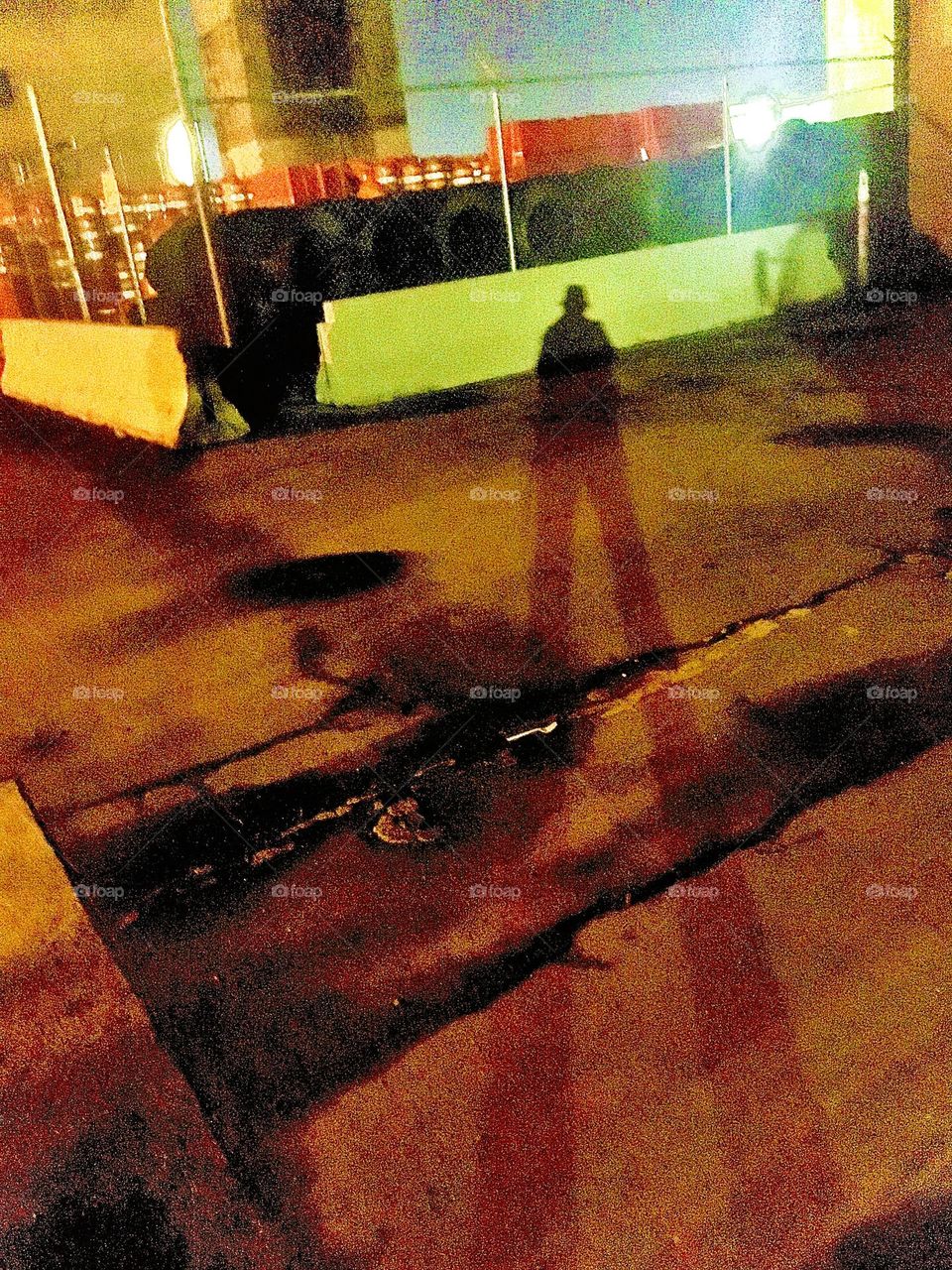 Petra dressed in her typical get-up in pants including the Fedora hat casts a dramatically elongated shadow over the parking lot underneath the Pulaski Bridge at Long Island City, Queens, NY. 2020. Hypnotic Productions