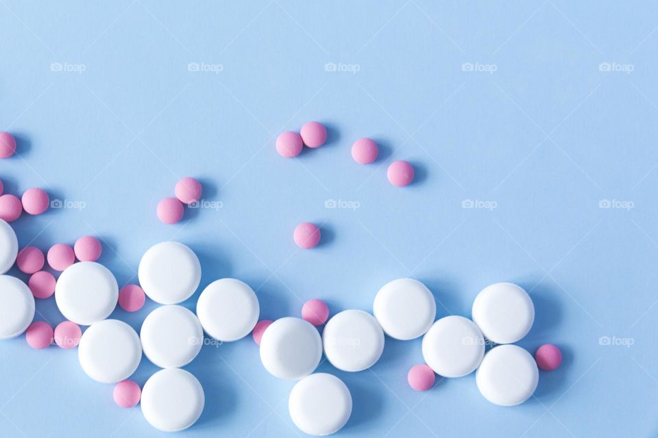 Pills and medicines lie on a blue background with an electrocardiogram of the heart.