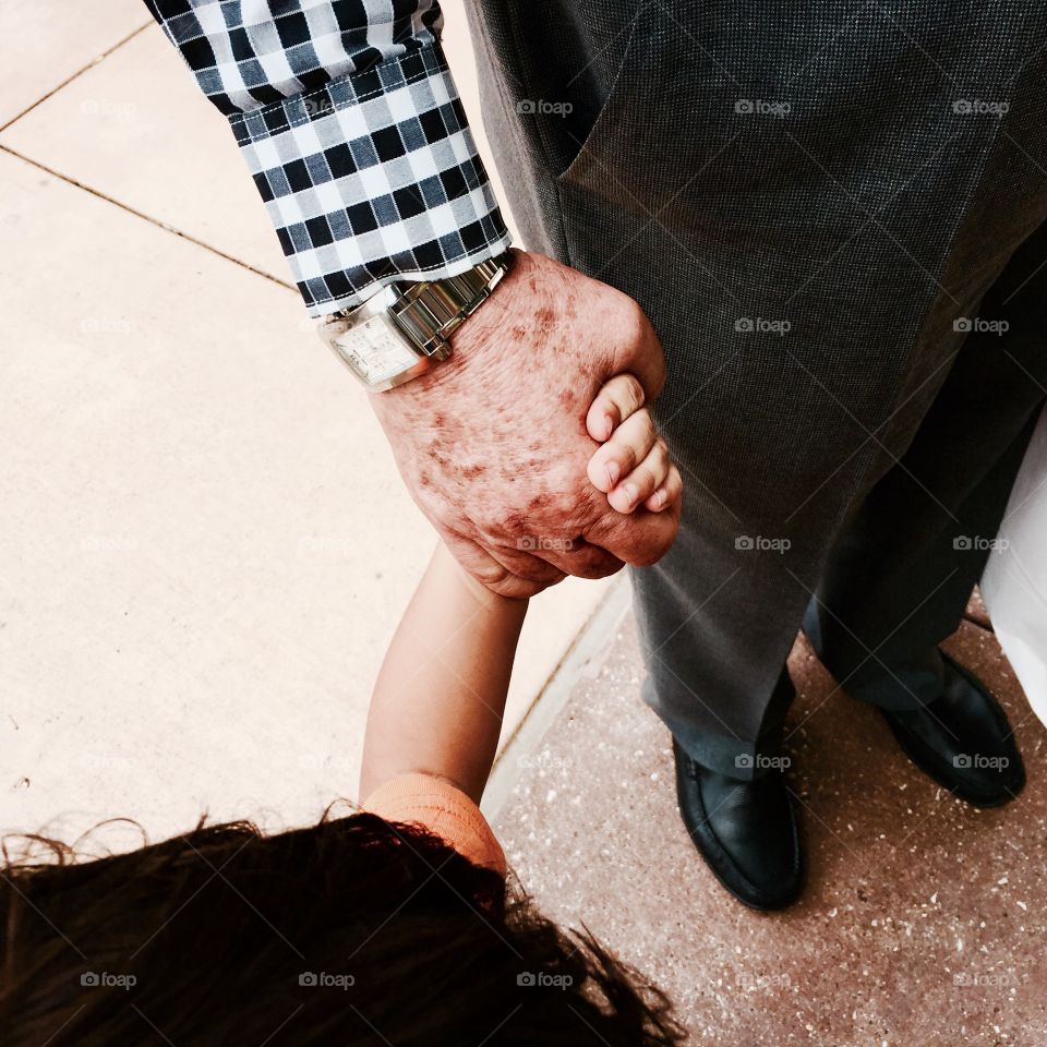 70 year old still working grandpa hold hands with grandchild. 