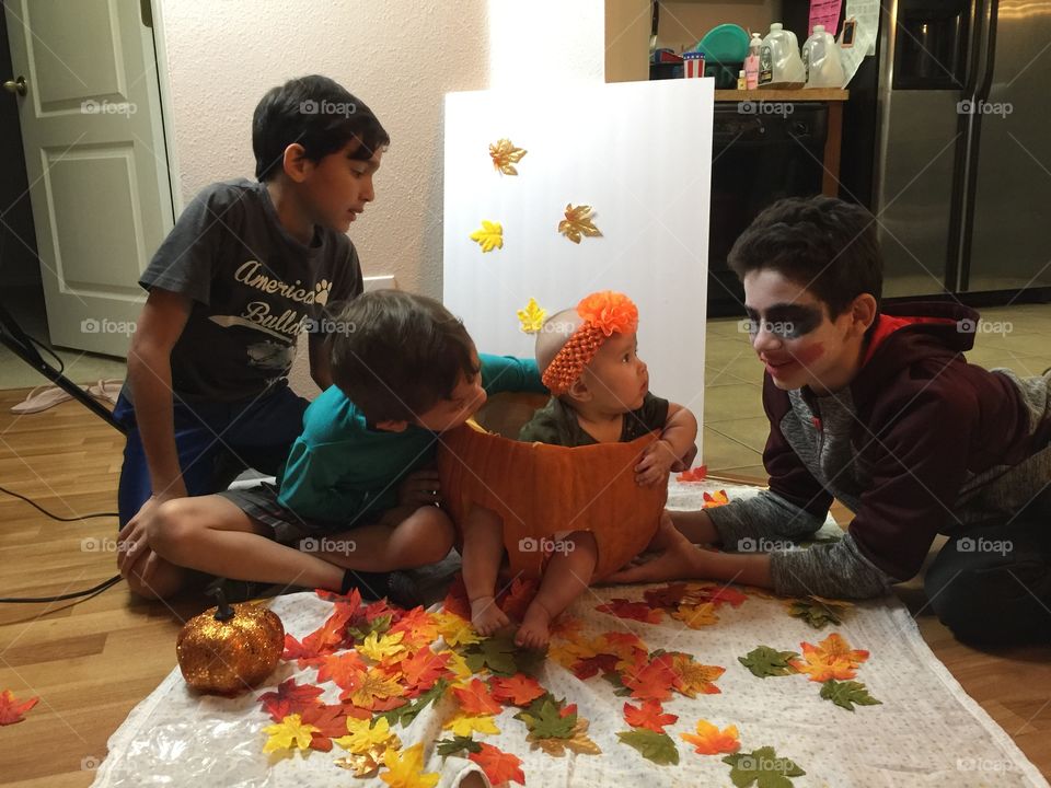 Curious baby in pumpkin with brothers 