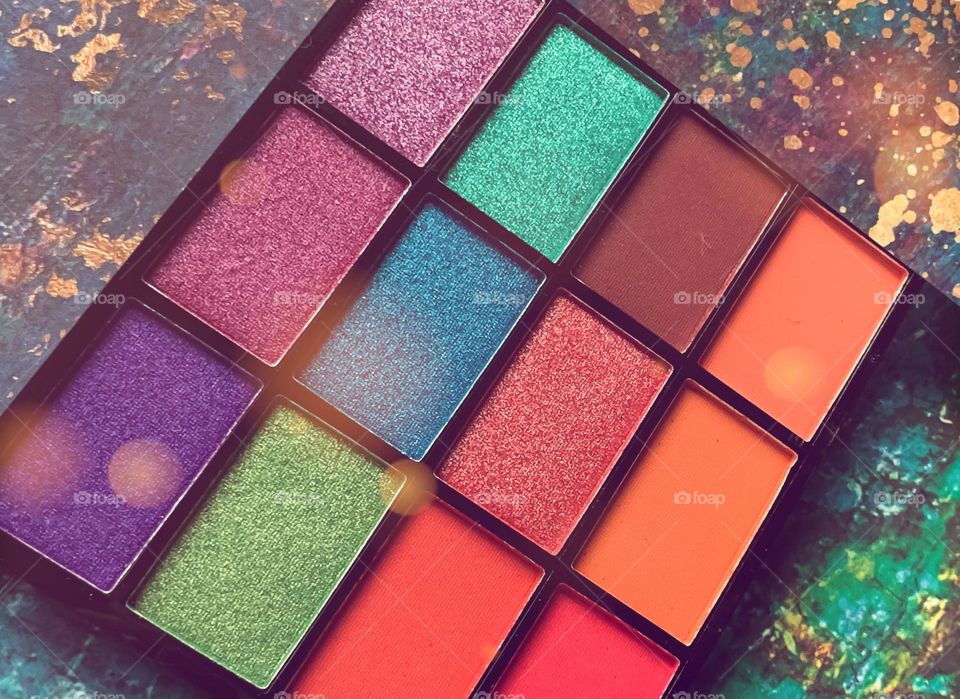 Vibrant cosmetic palette on a colourful background with bokeh overlay 