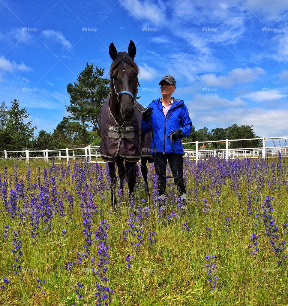 Mature woman standing with black horse