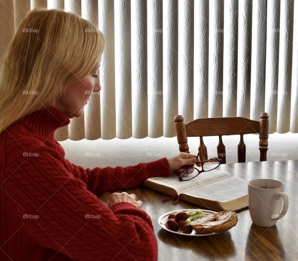 Woman reading the Bible at the breakfast table