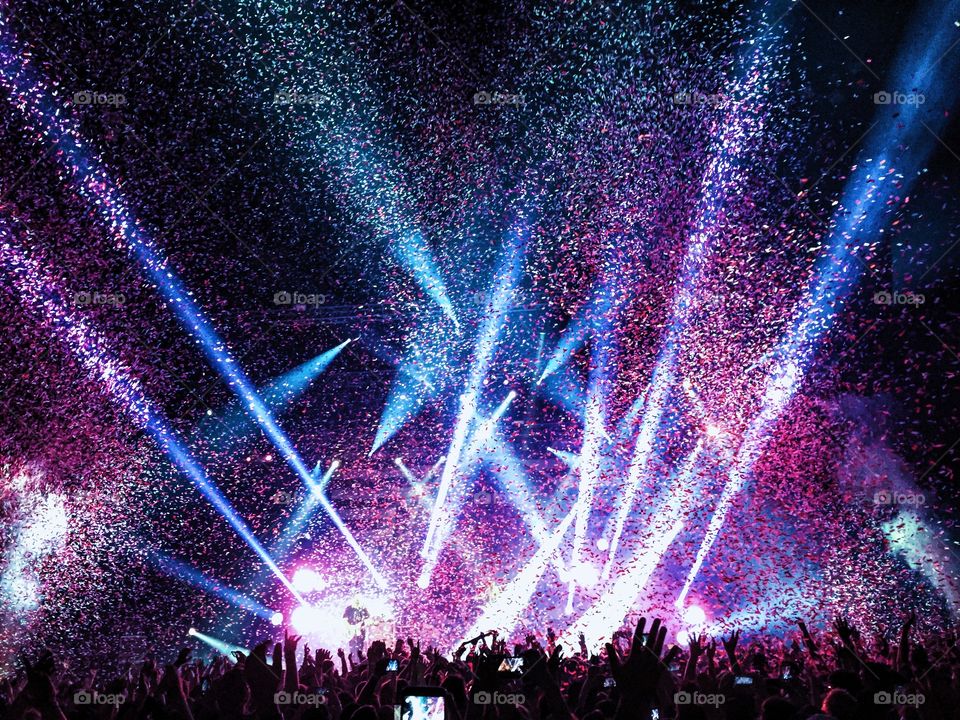 Confetti falls on an enthusiastic crowd at the end of a rock concert 