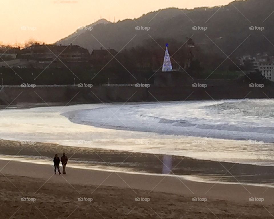 Walking in the sand with Christmas tree in the background, Spain