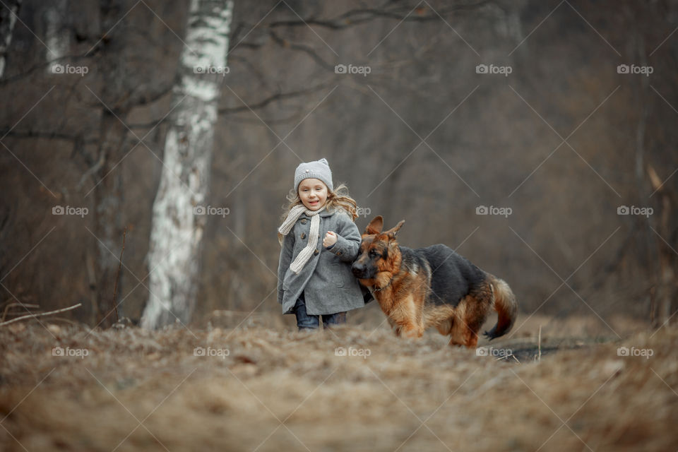 Little girl with German shepherd young male dog walking outdoor at spring day