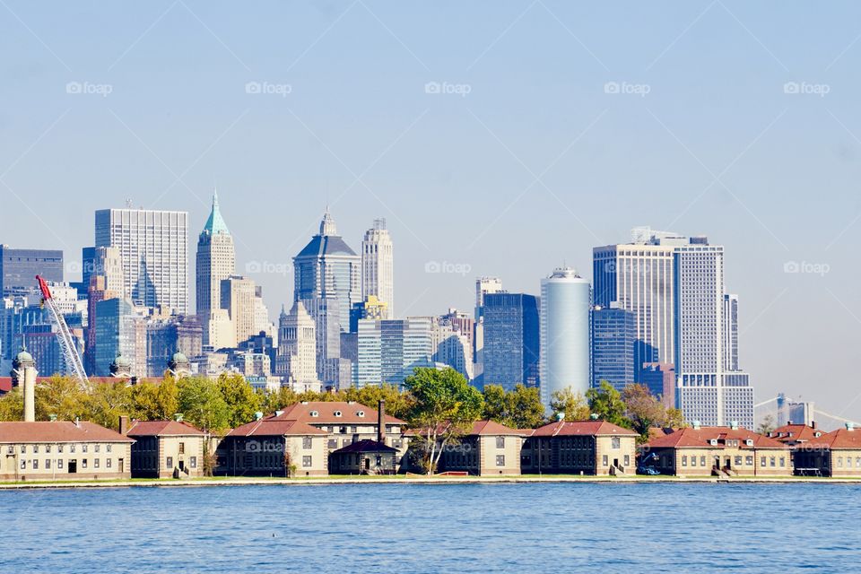 View from Liberty State Park- The buildings of  historic  Ellis Island looms in the  foreground against the backdrop of the buildings of downtown Manhattan. 