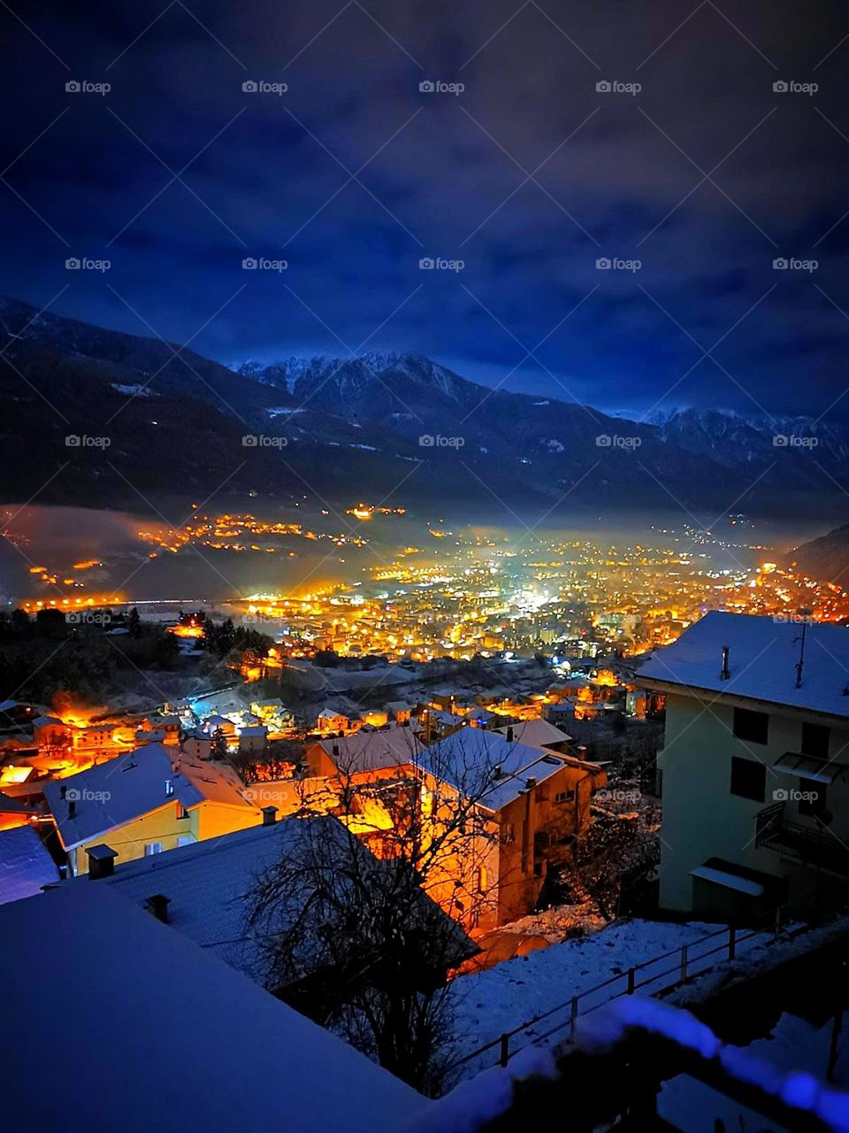 Italy. Winter night of the city in the mountains. View from above