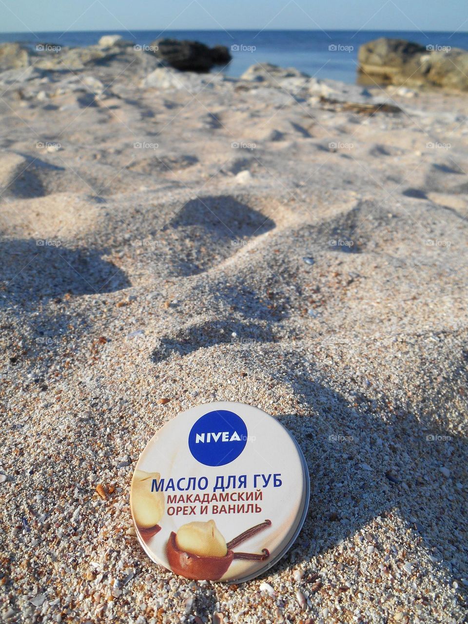 lip balm Nivea in the hand on a sand sea shore, vacation product