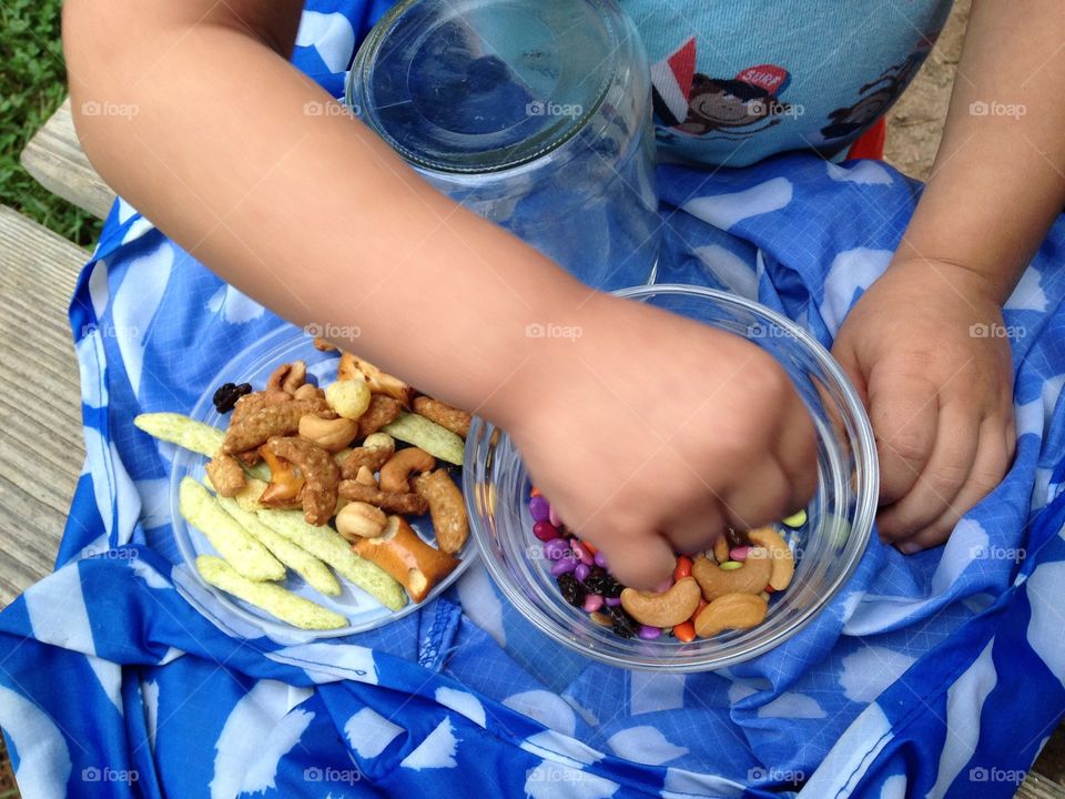 Toddler eating snacks from jars.