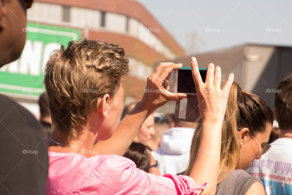 A guy in the crowd is taking a picture of the artist performing on stage
