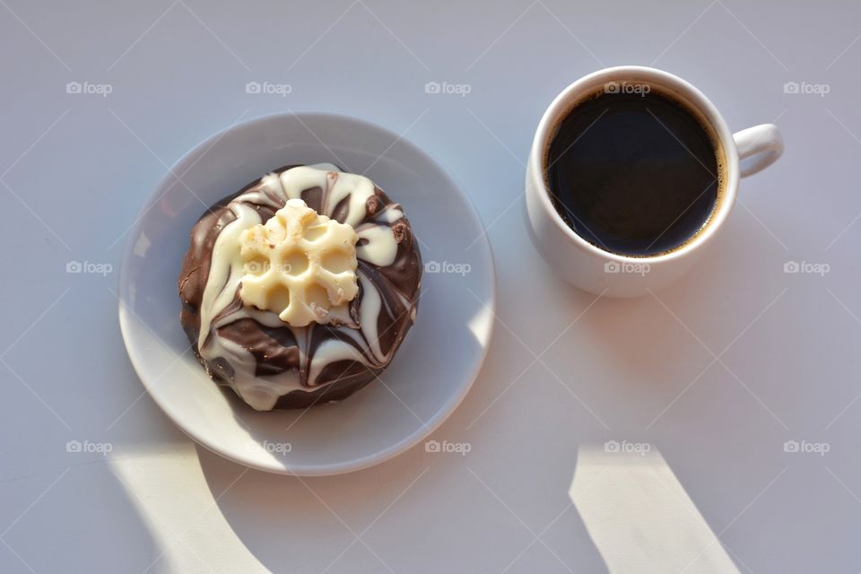 cup of coffee and cake in sunlight on a white top view background