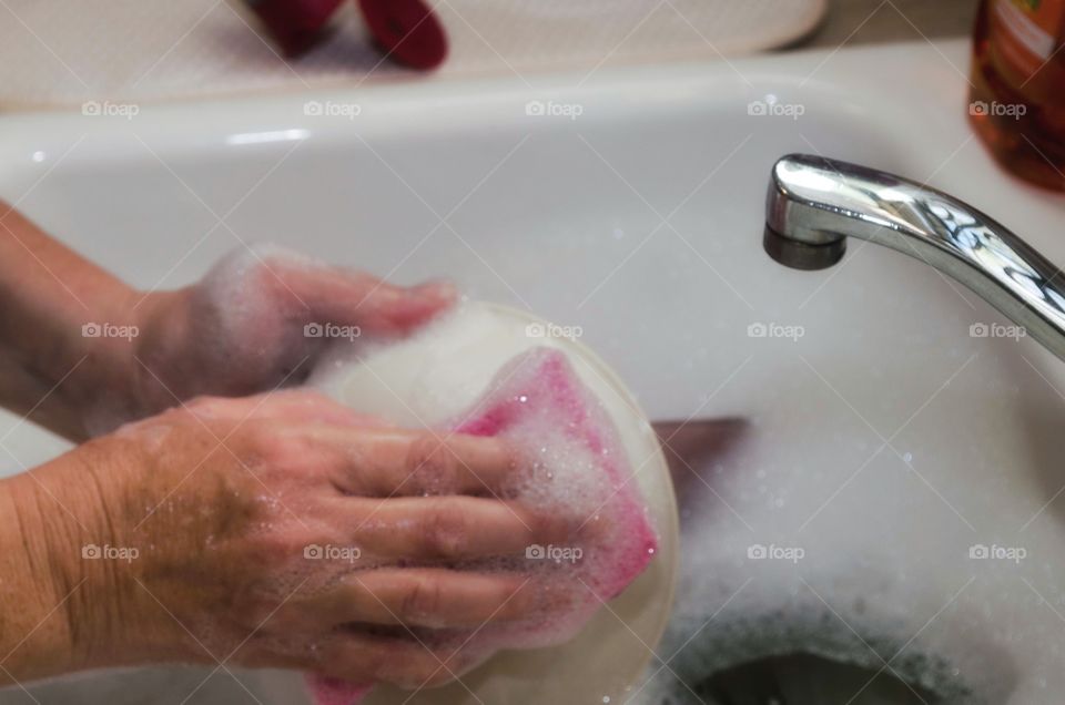 A person washing bowl in sink