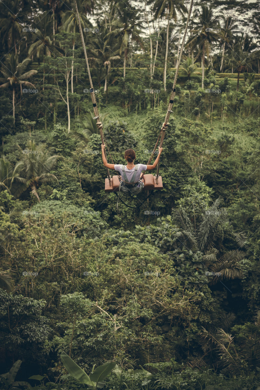 Girl riding on a swing in the jungle.  Bali Island.