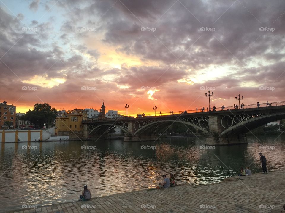 Spanish Skies & Keen Eyes. The sun setting in Sevilla, Spain behind the Puente de Isabel 