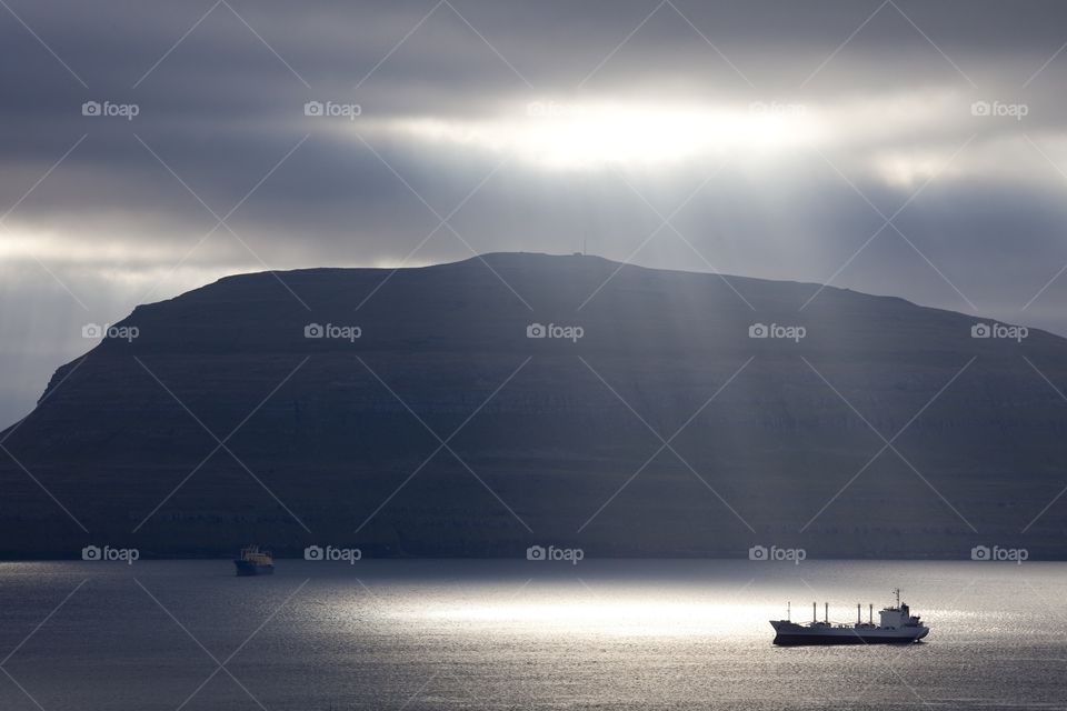 The sun illuminates the bay in the Faroe Islands.. Trading vessels stand on spot-check in port on Faroe Islands