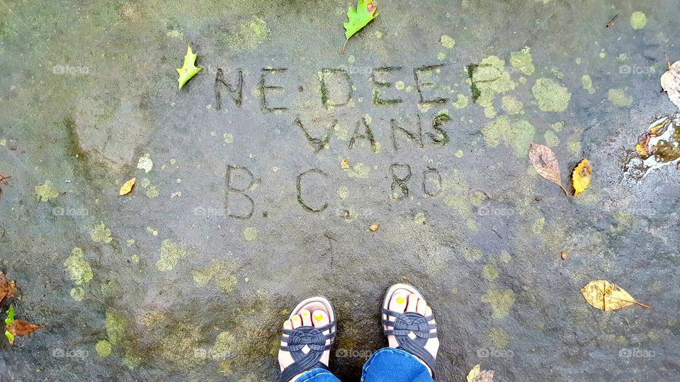 Name graffiti carved into a boulder in the forest in autumn.