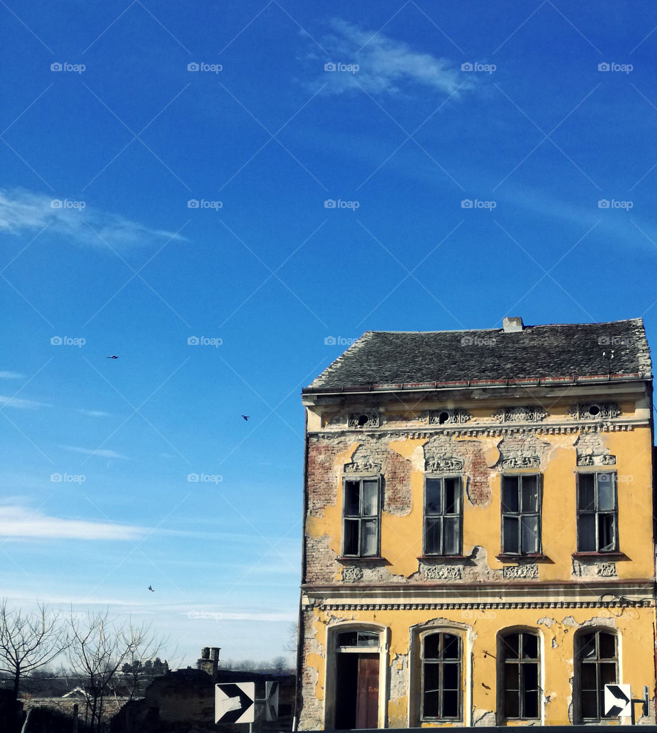 a very old yellow house and blue sky. ruin