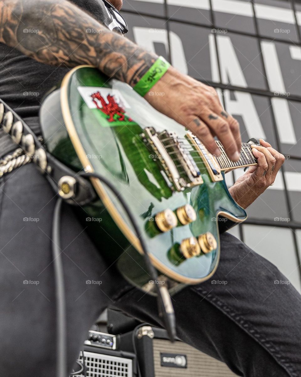 Close up of a man with tattoos playing a green guitar
