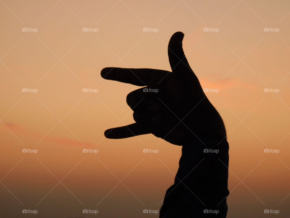 Hand posture silhouette with sunset light background.