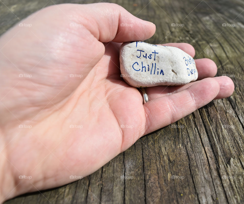 Hand holding a stone with an affirmation written on it