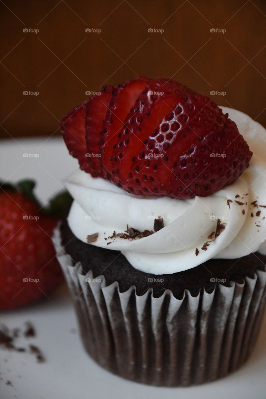 chocolate cupcake with white icing and strawberries