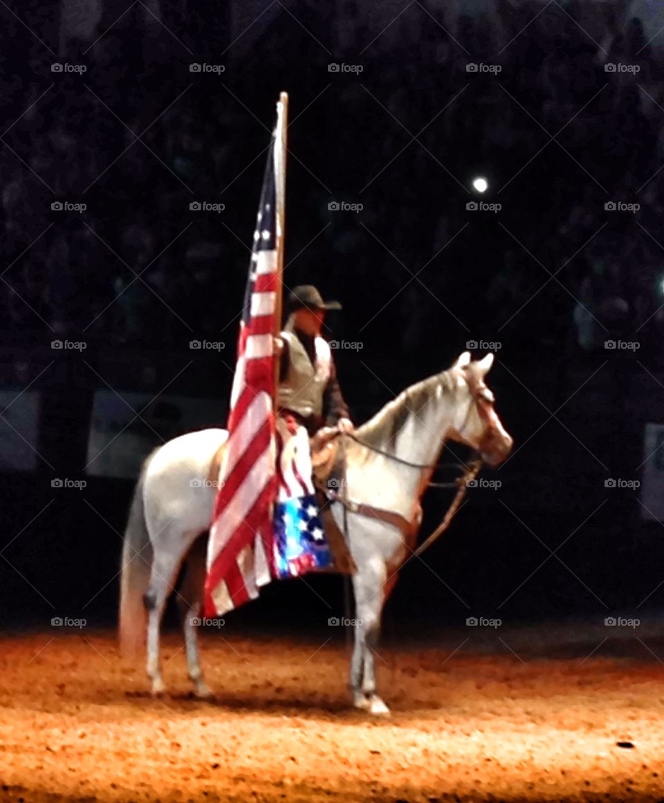 Please rise. Woman riding a horse and holding American flag
