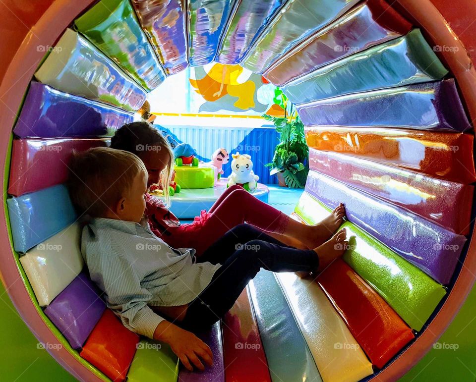 Two kids in a colourful tube