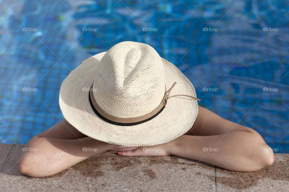 Woman in a hat in the pool, summer vacation