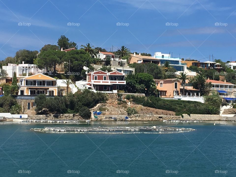 Some more of the houses along the Menorcan coast, an area to dock boats can be seen in the water although none can be seen. Is everybody out?