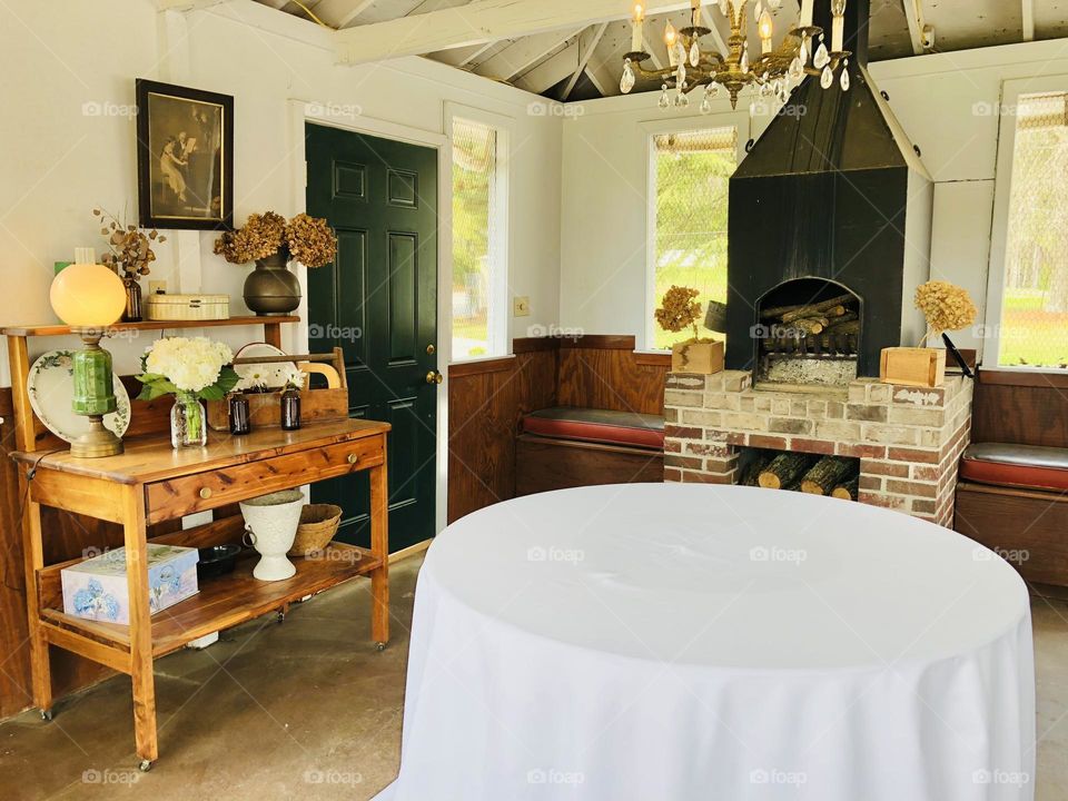 Homey cafe corner with round table and bench seating. Fireplace and antique furniture, chandelier and decor.