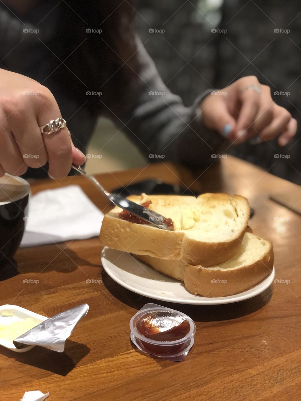 Hand spreading jam and butter on a toast