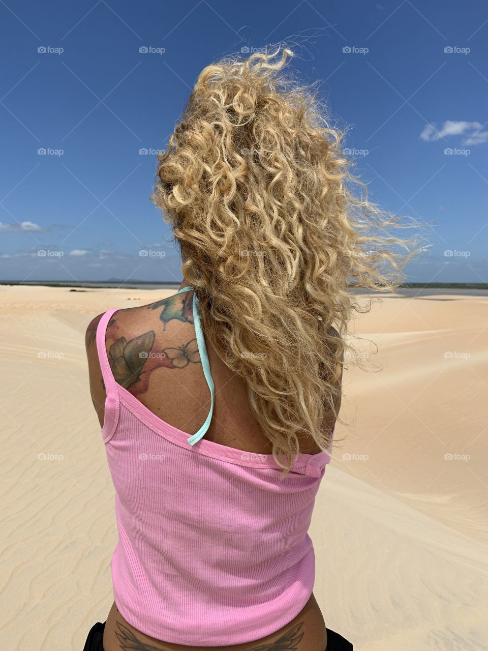 Blond. Hair woman with pink shirt against desert 