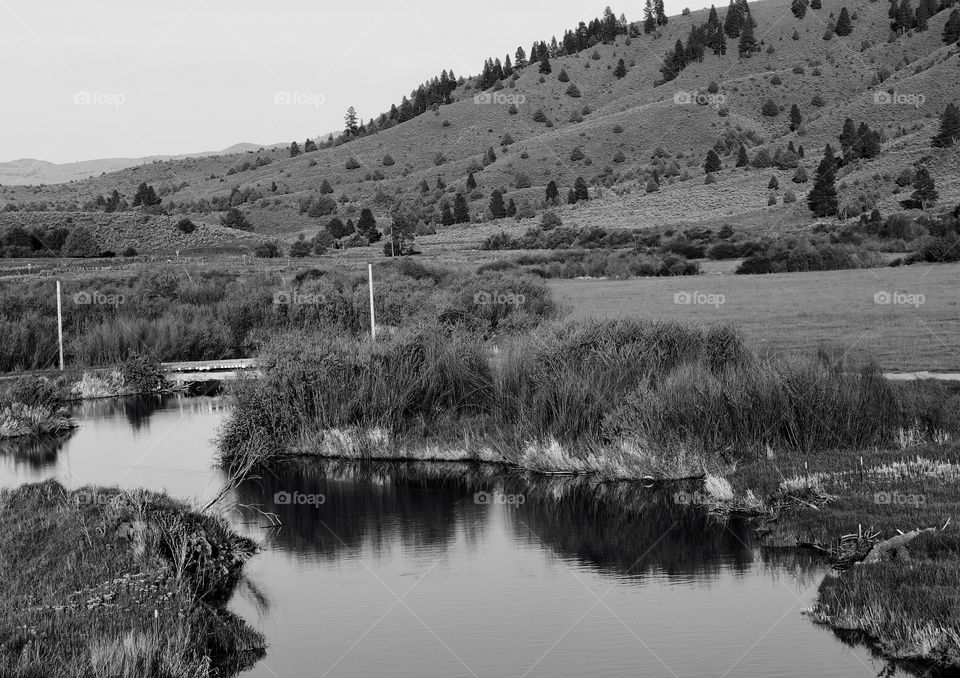 A creek flowing through fields and hills 