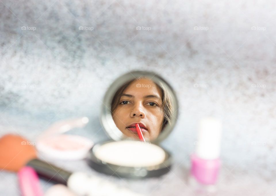 A woman applying lipstick on lips.