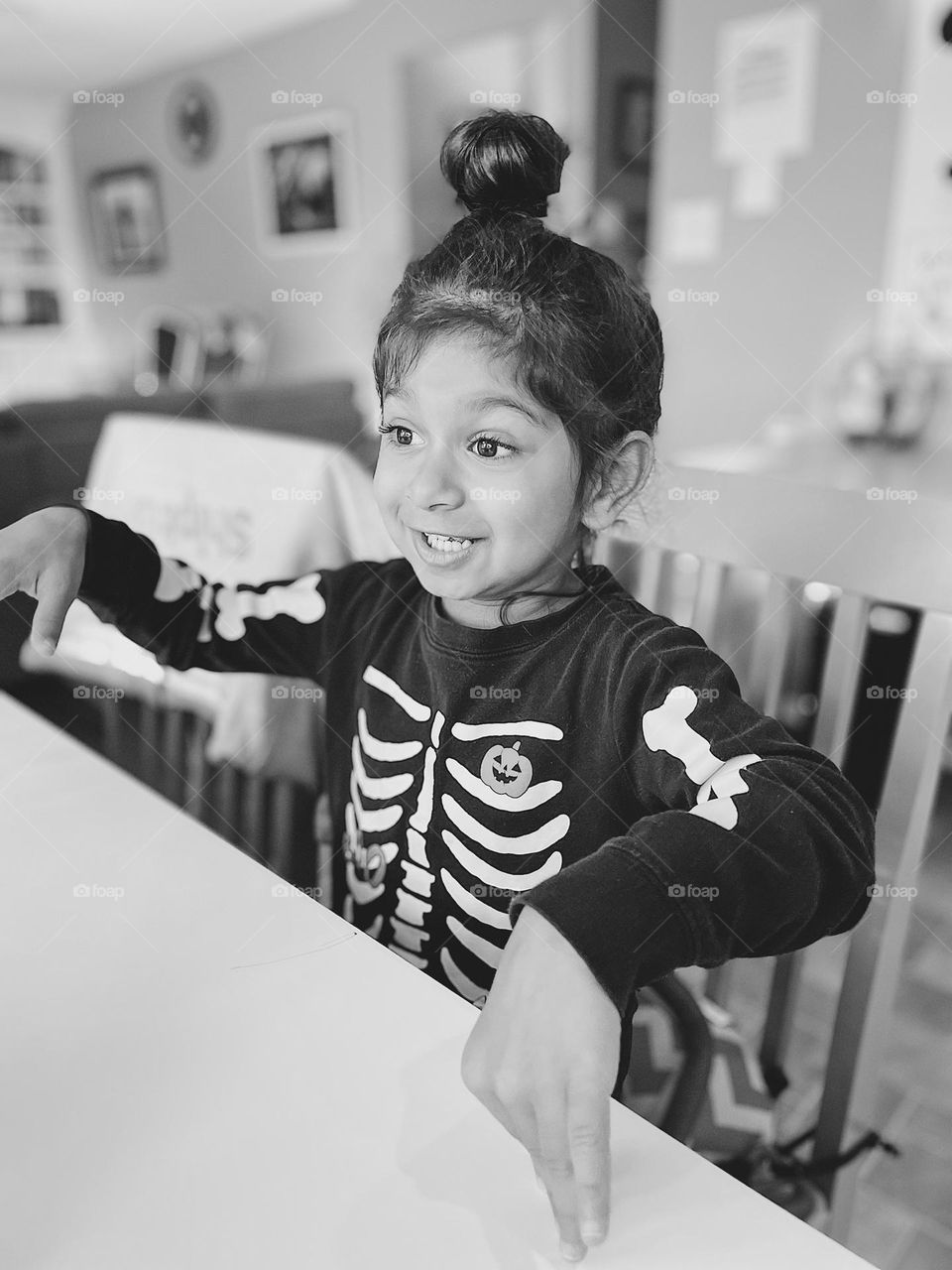 Little girl acts like a skeleton, being silly for Halloween, black and white image of little girl, portraying a skeleton 