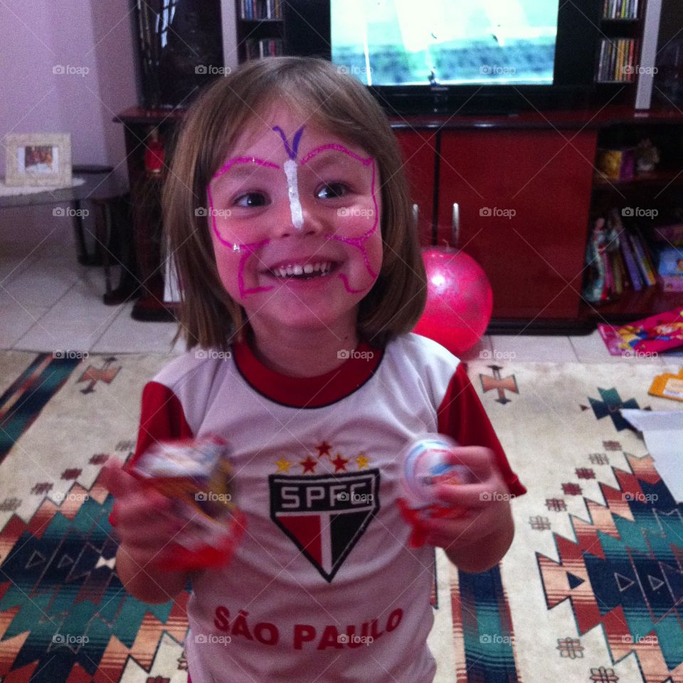 Uma garotinha muito feliz, torcedora do São Paulo Futebol Clube, fazendo bagunça. 