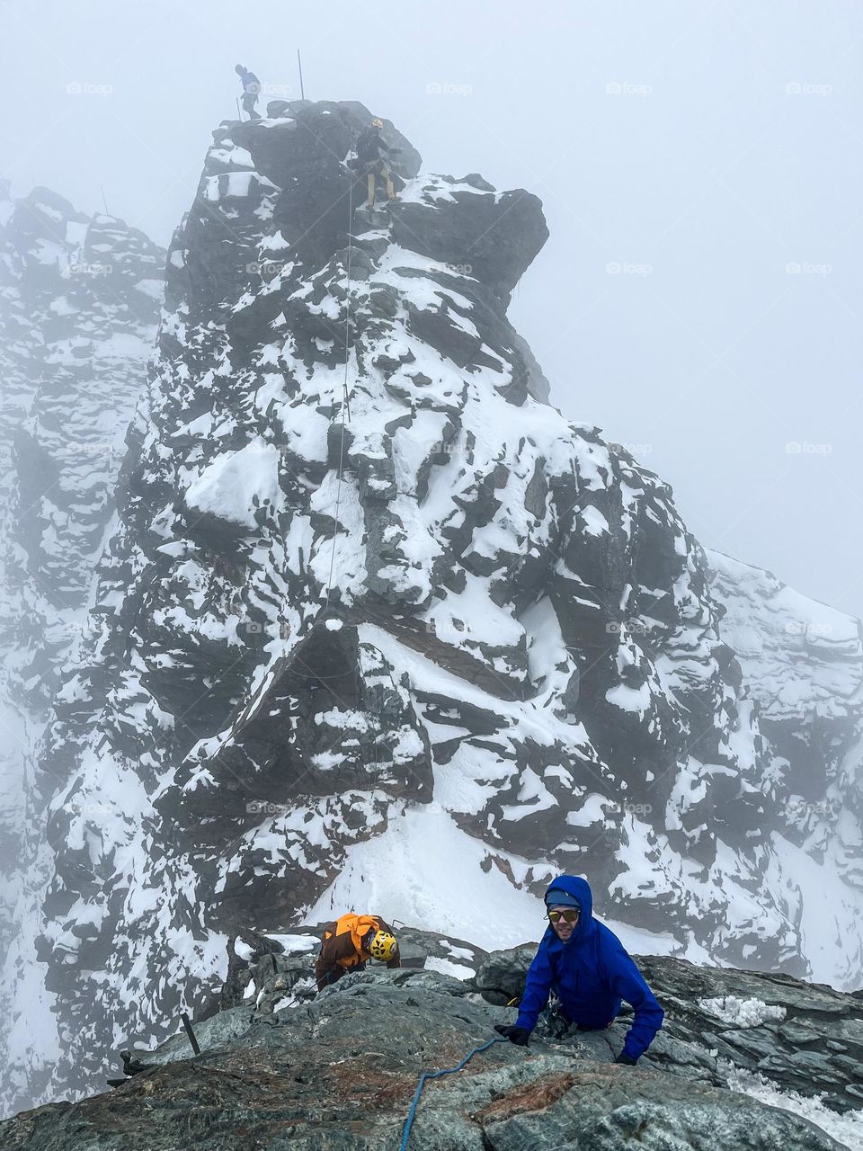 Climbers on the walls of the highest summit of Austria - Grossglockner peak on a foggy sumer day. 