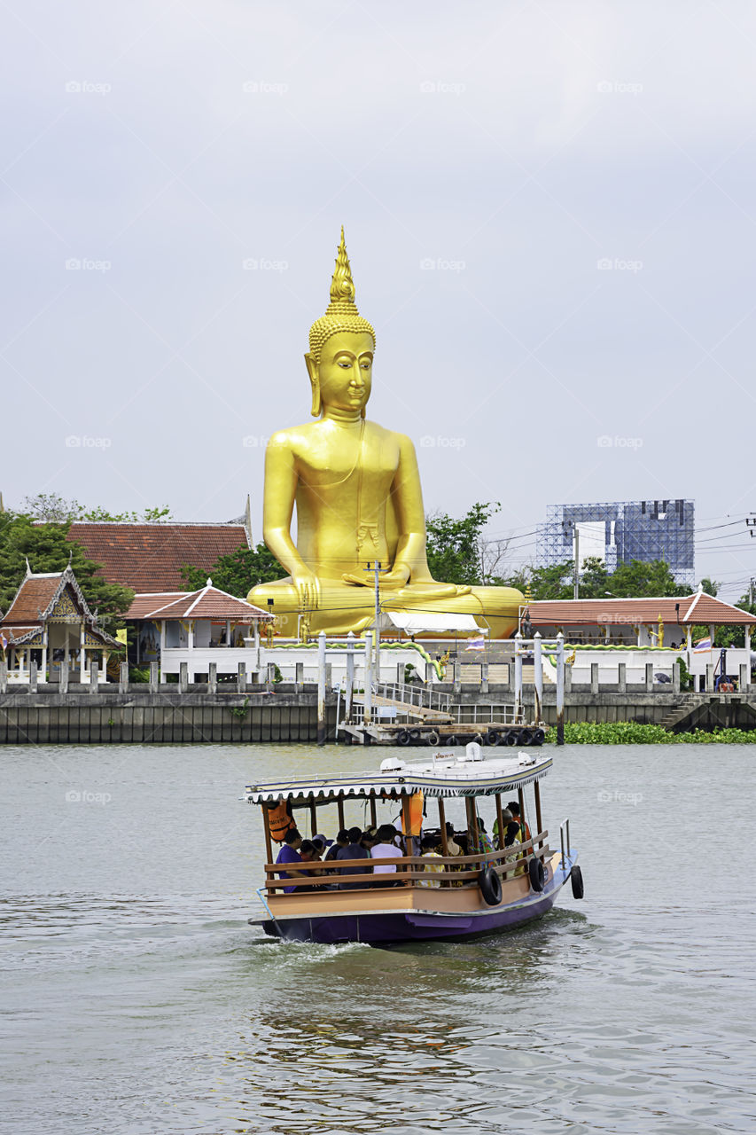 Ships crossing in Chao Phraya River and Big Buddha golden Background sky and clouds at Wat Bang Chak in Nonthaburi , Thailand. April 16, 2019