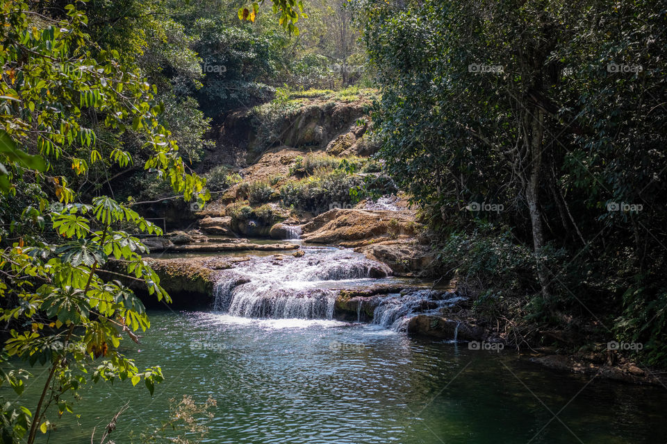 Waterfall in the middle of the  jungle, being lit by the sun