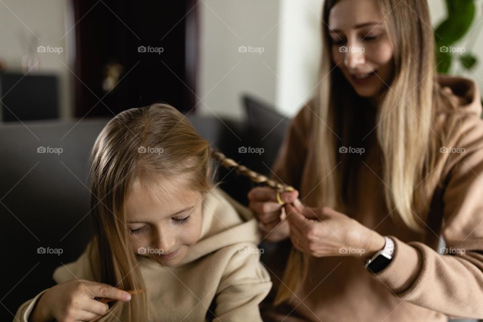 Mother braiding hair for daughter at home