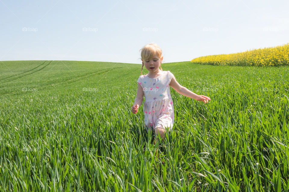 Little girl three years old runni g in the grass fueld outside Malmö Sweden.