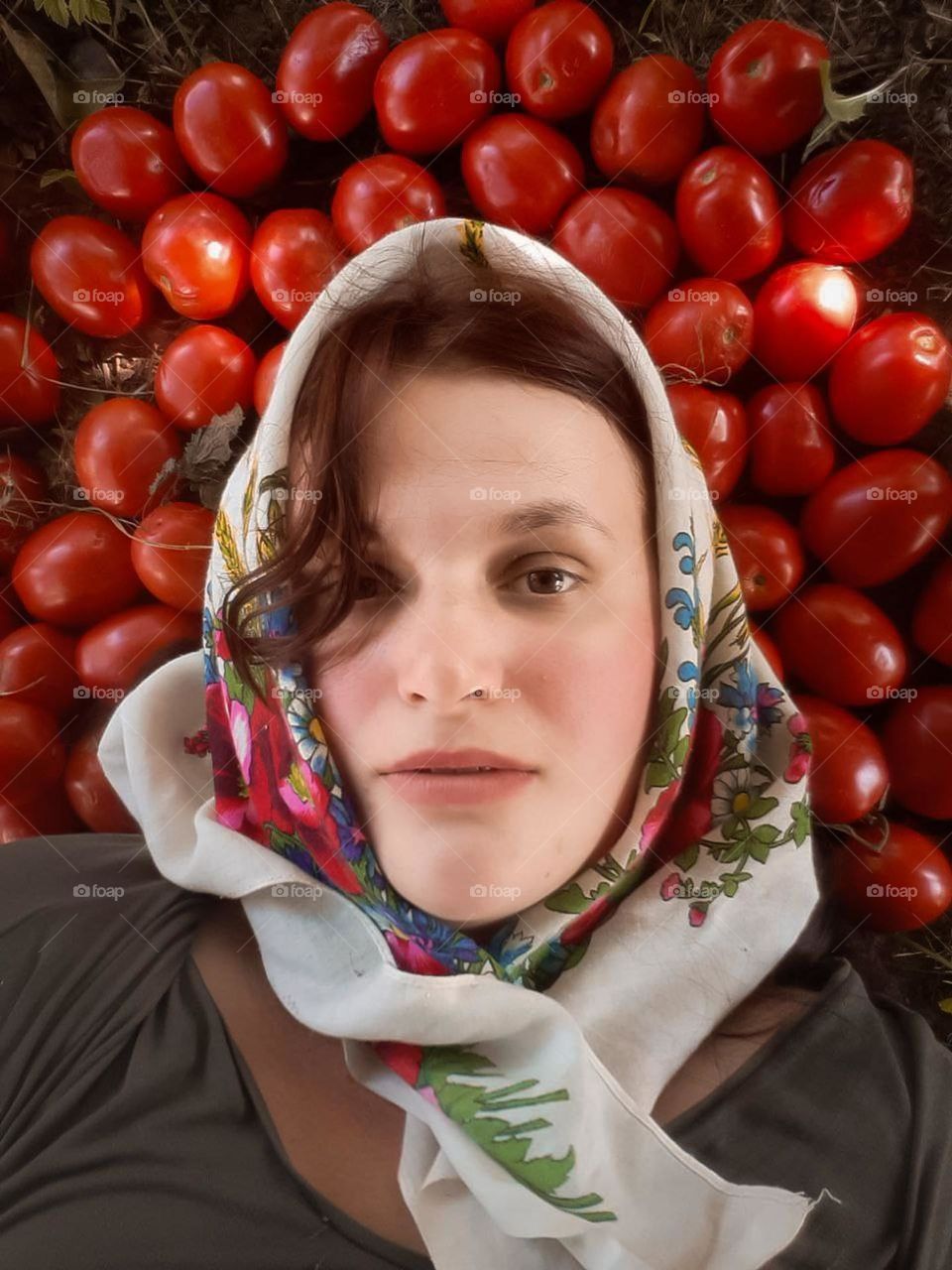 an original portrait of a young village girl in an embroidered scarf among home-grown tomatoes