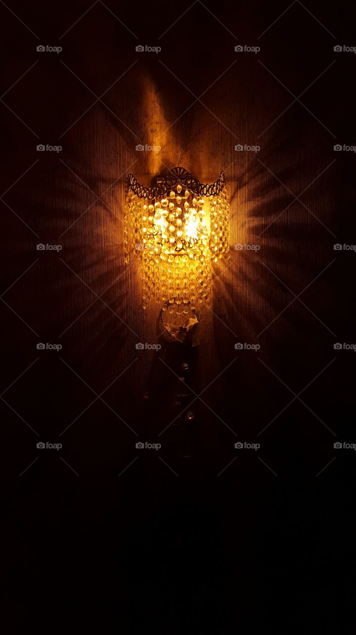 a wall light hanging on a wall and lit in a dark room