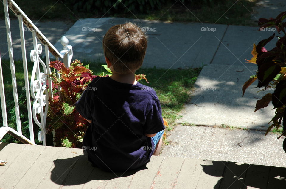 Taking A Break. Child sitting on porch steps, taking a break from play.