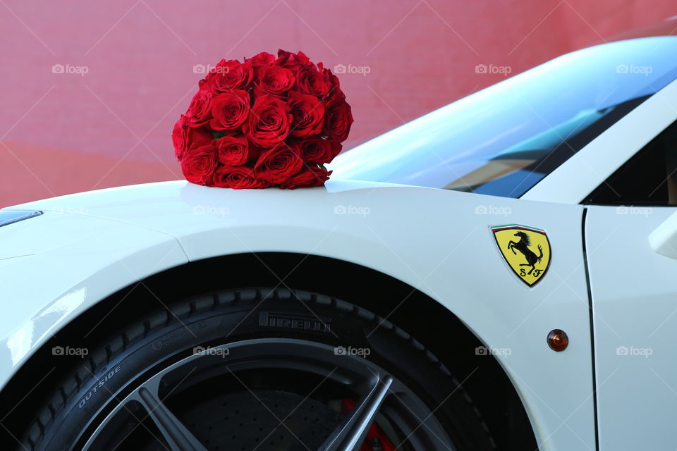 Ferrari and flowers. Exotic sports supercar and red roses