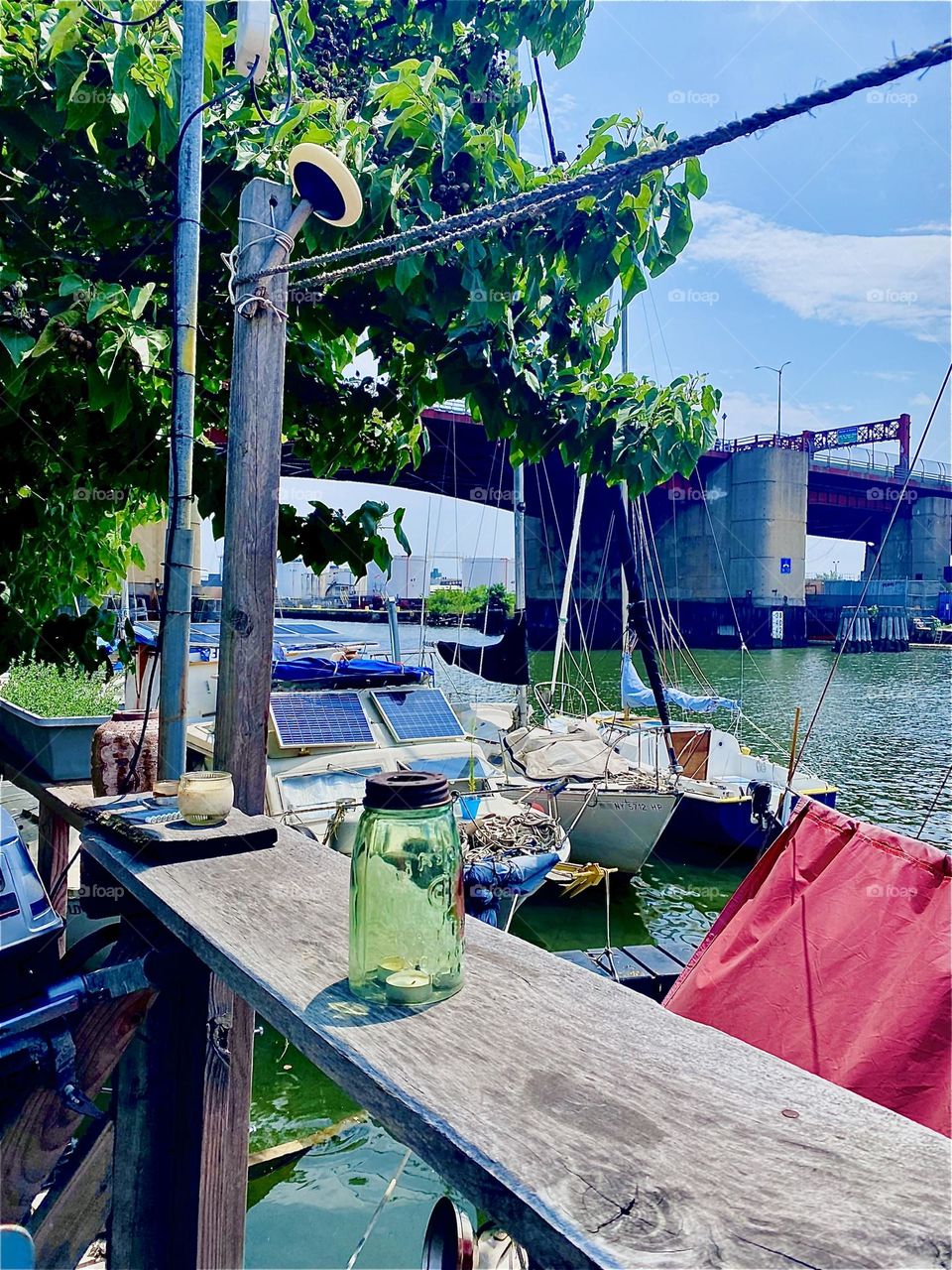Looking in the direction of the „Pulaski Bridge“ from the homemade veranda at „Newtown Creek“ we can see more boats as well as the lush tree lined shore. 2023. Hypnotic Productions