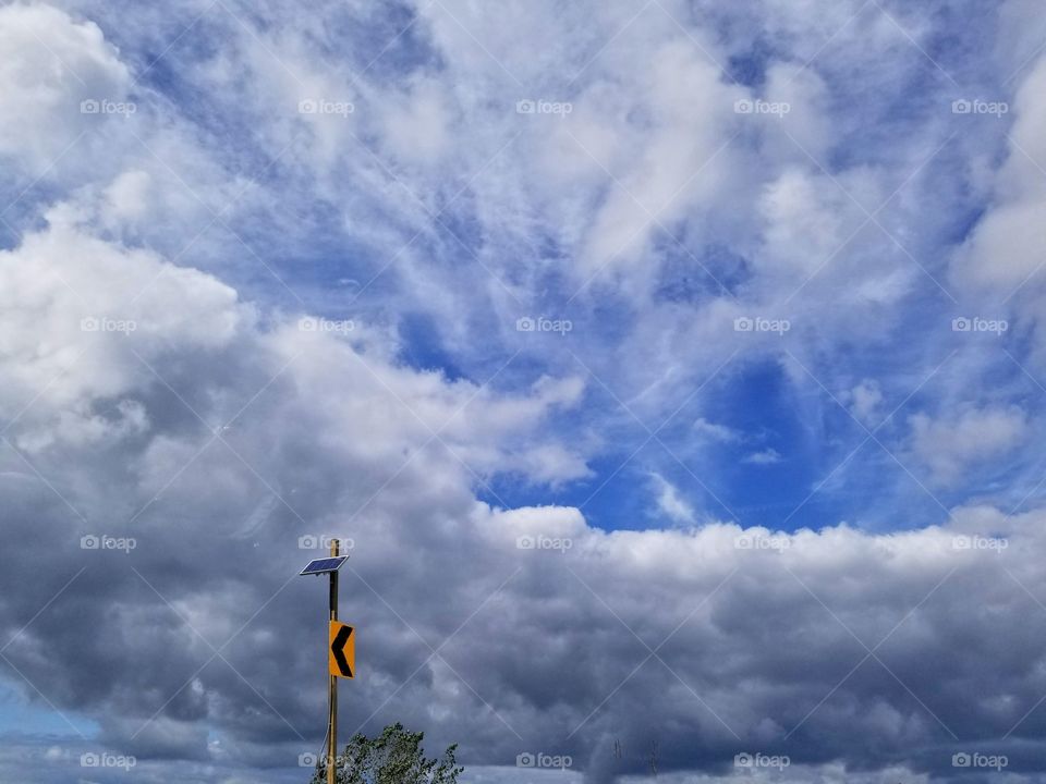 Solar panel on a street sign with a beautiful display of clouds