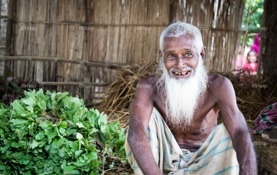 Old man in bangladesh with white beard selling vegetables